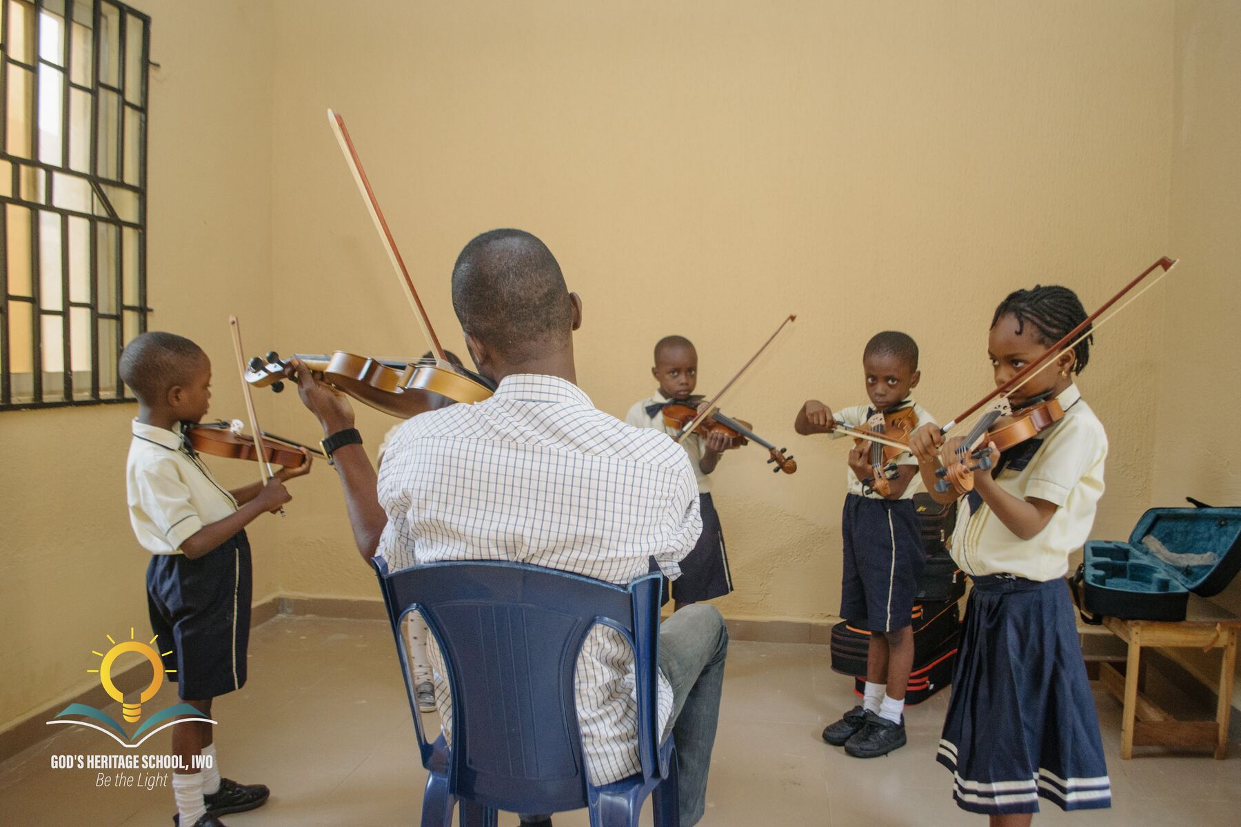 GHSI pupils practising violin together with their music teacher